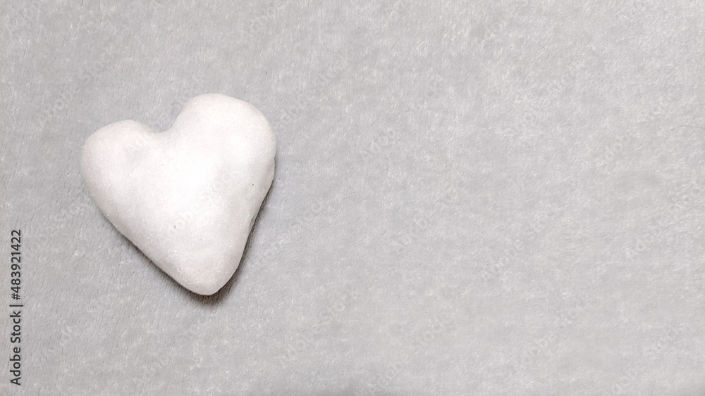 A cold snowy heart made with love lies on a gray plaid A cold snowy heart made with love lies on a gray plaid