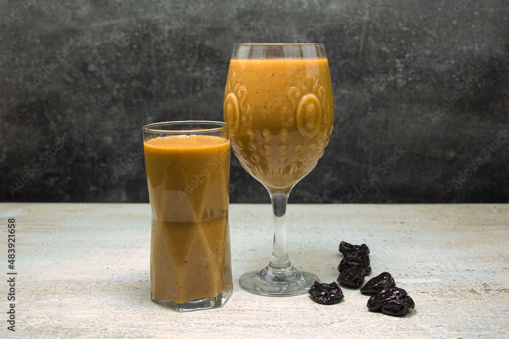 Fruit smoothie in a glass on a table decorated with prunes. Side view.