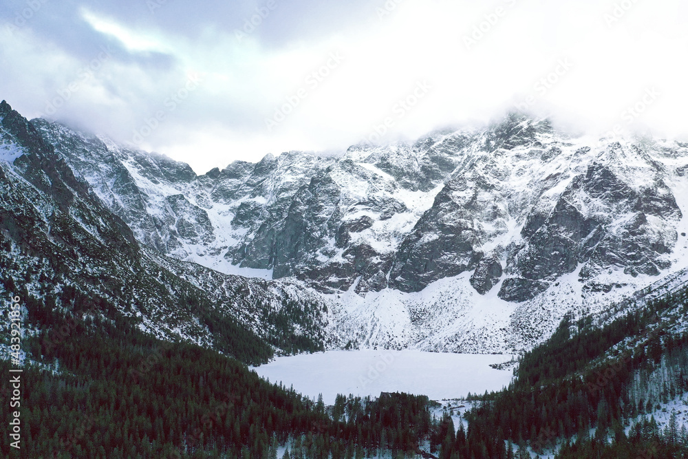 Obraz premium High winter mountains peak in Morskie Oko frozen lake in Poland with winter forest.