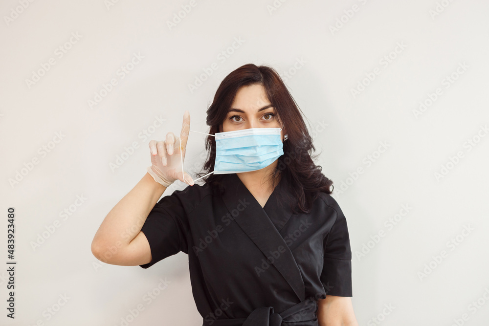 Woman in latex gloves is putting on protective mask on her face, cosmetologist or beauty specialist. Woman in latex gloves is putting on protective mask on her face, cosmetologist or beauty specialist.