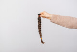 Close up photo of woman holding braided brown hair for donation.