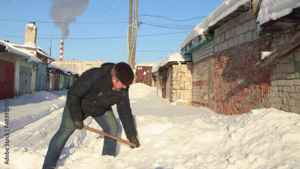 A man in warm clothes with a shovel cleans the path from snow. Clear, sunny cool winter day, blue sky. There are snowdrifts all around. Climate change, city, there was a snowstorm. UHD 4K A man in warm clothes with a shovel cleans the path from snow. Clear, sunny cool winter day, blue sky. There are snowdrifts all around. Climate change, city, there was a snowstorm. UHD 4K