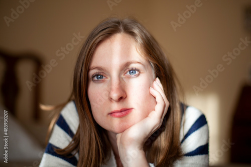Mujer rubia de ojos azules junto a la ventana photo