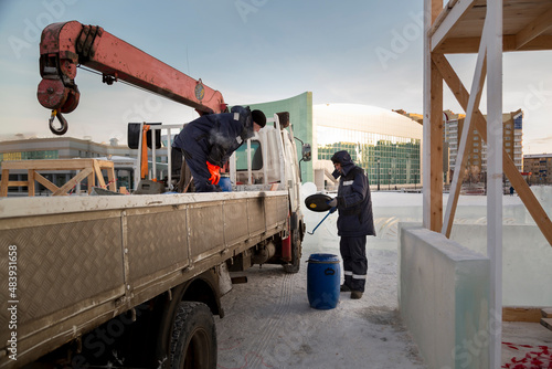 Workers are assembling ice blocks on the frame of a wooden slide