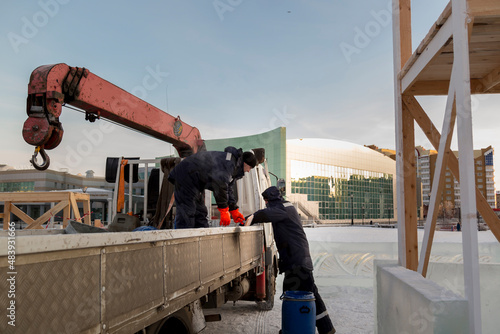 Workers are assembling ice blocks on the frame of a wooden slide