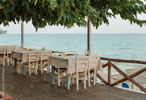 Fototapeta Naklejka Na Ścianę i Meble -  Cafe with empty tables near the sea. Open air restaraunt near sea. Greek tavern.