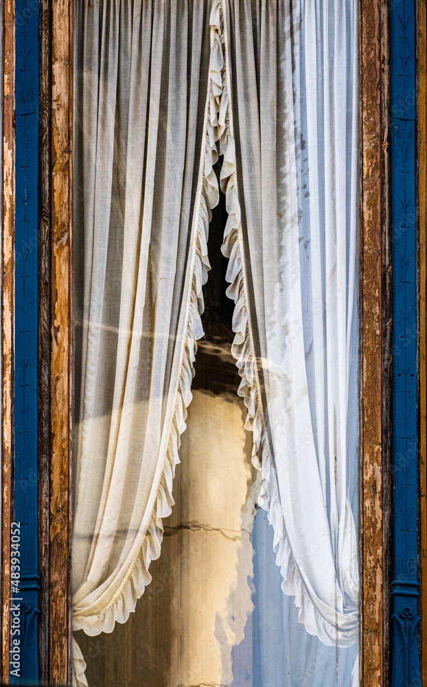 Ventana modernista de madera con su cortina bellamente bordada en una casa antigua y centenaria de Granollers Ventana modernista de madera con su cortina bellamente bordada en una casa antigua y centenaria de Granollers