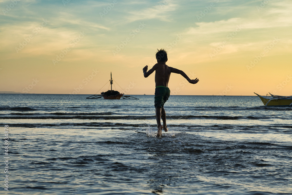 Fototapeta premium Water play at sunset at Bulalacao fishing village, oriental Mindoro, Philippines. Fun, joy, excitement. Village lifestyle. 