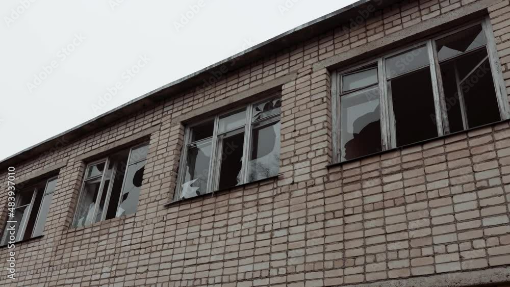 Broken windows in a brick two-story building. An abandoned vandalized building in a war zone against a gray sky. High quality 4k footage Broken windows in a brick two-story building. An abandoned vandalized building in a war zone against a gray sky. High quality 4k footage
