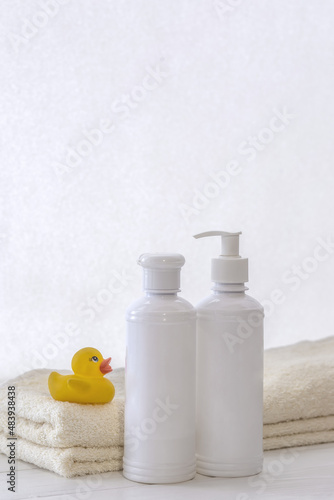 Set of white cosmetic bottles mockup with a towel and a natural soap on a white table. Hygiene and healthy life concept. Close up, selective focus