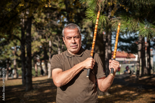 Escrima and kapap instructor demonstrates sticks fighting techniques in park