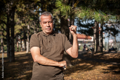 Escrima and kapap instructor demonstrates sticks fighting techniques in park photo