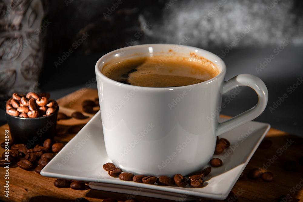 Fototapeta premium White cup and saucer of espresso coffee on a background of scattered coffee beans. Making coffee.