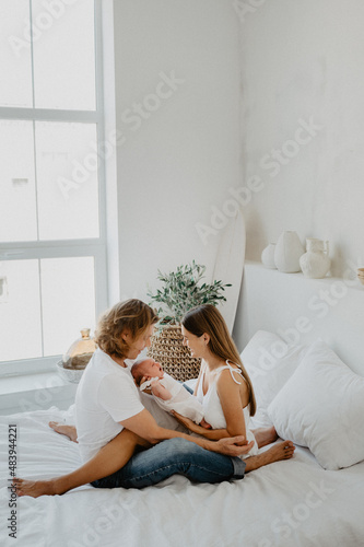 Young mom and dad are holding a newborn in their arms. The family holds a newborn baby girl in their arms.