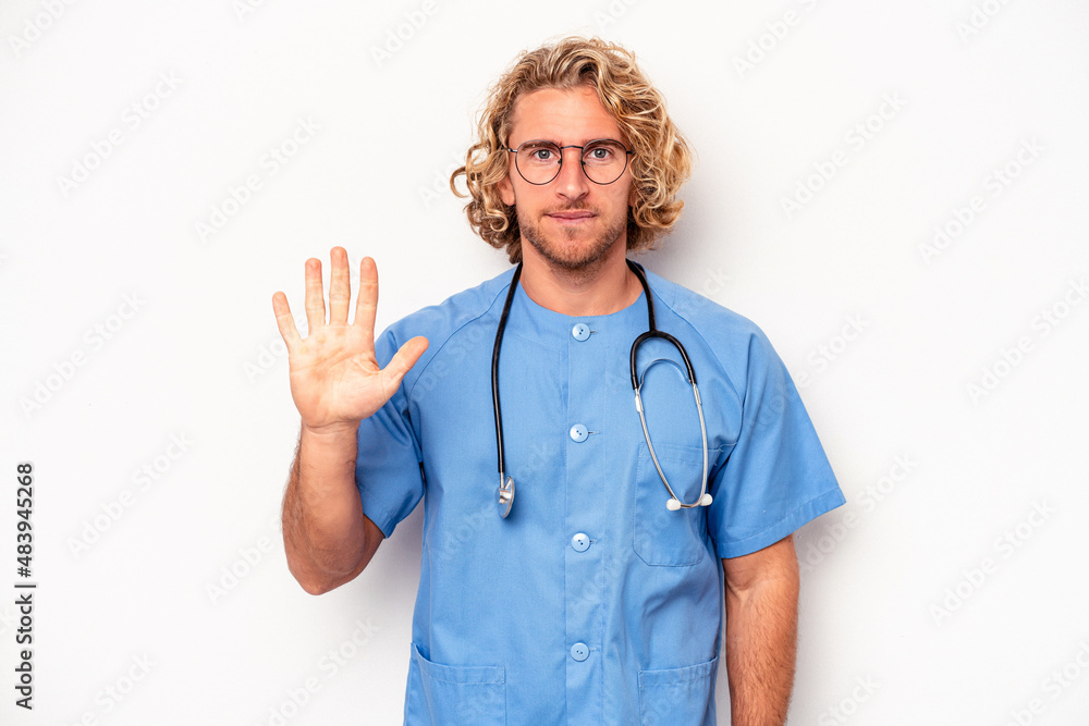 Young nurse caucasian man isolated on white background smiling cheerful showing number five with fingers.