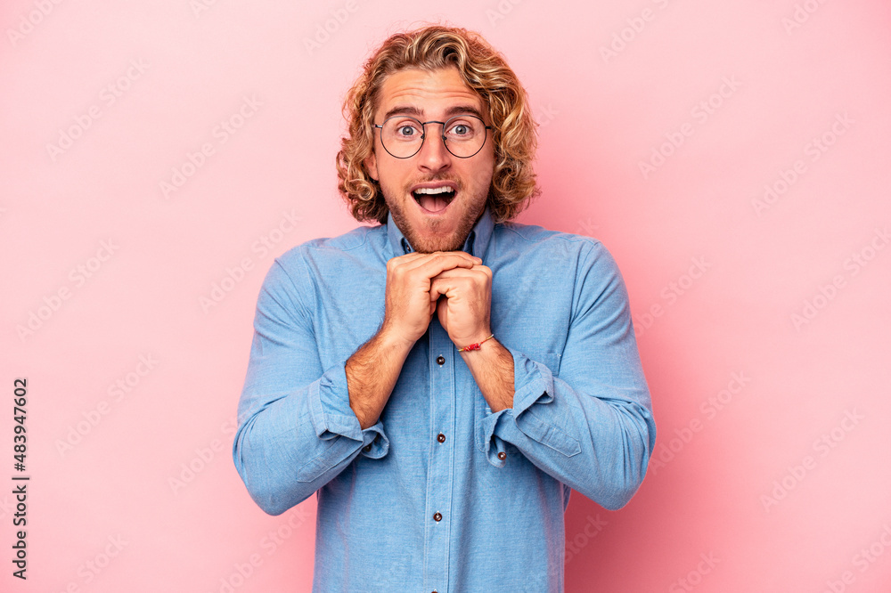 Young caucasian man isolated on pink background praying for luck, amazed and opening mouth looking to front. Young caucasian man isolated on pink background praying for luck, amazed and opening mouth looking to front.