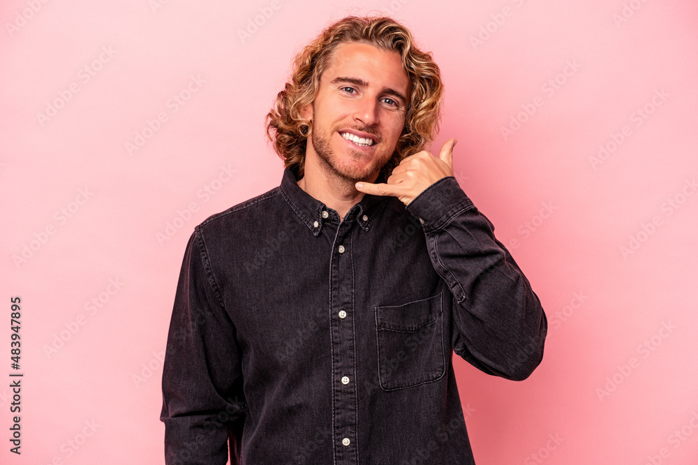 Young caucasian man isolated on pink background showing a mobile phone call gesture with fingers. Young caucasian man isolated on pink background showing a mobile phone call gesture with fingers.
