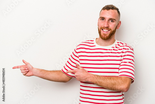 Young caucasian man isolated on white background excited pointing with forefingers away.