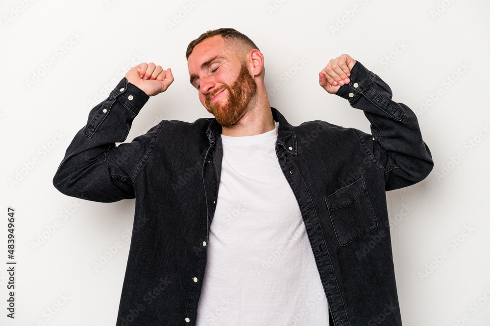 Naklejka premium Young caucasian man isolated on white background stretching arms, relaxed position.