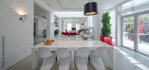 Modern interior of spacious living room. White dinner table and chairs.