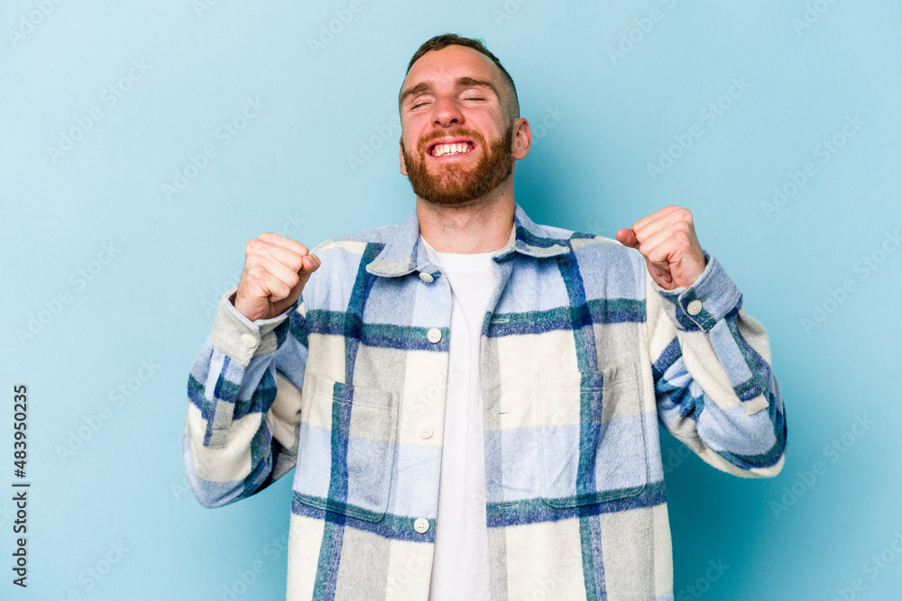 Young caucasian man isolated on blue background celebrating a victory, passion and enthusiasm, happy expression. Young caucasian man isolated on blue background celebrating a victory, passion and enthusiasm, happy expression.