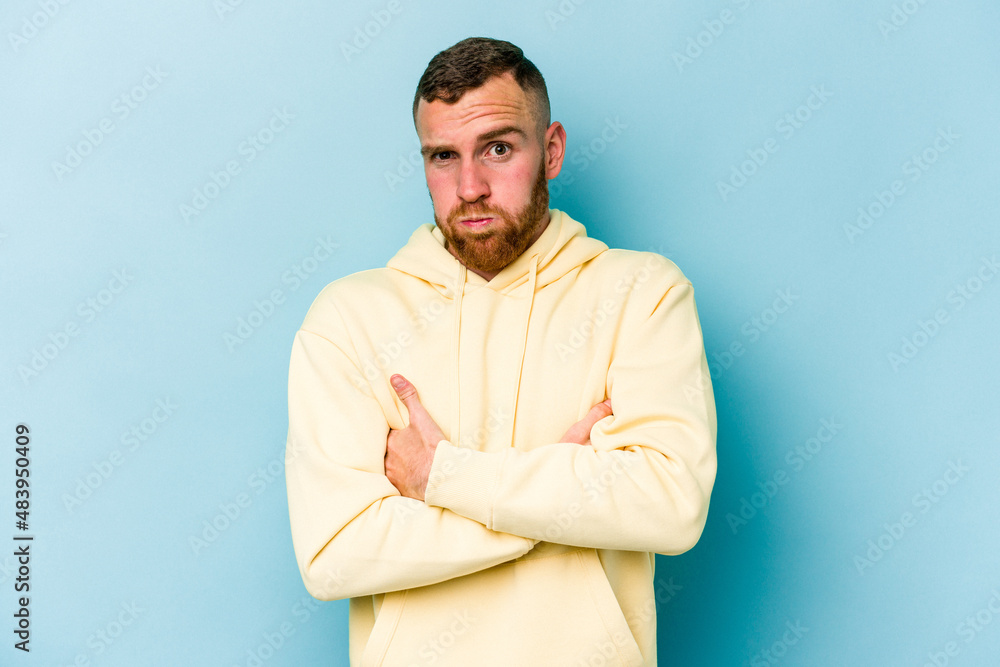 Young caucasian man isolated on blue background blows cheeks, has tired expression. Facial expression concept. Young caucasian man isolated on blue background blows cheeks, has tired expression. Facial expression concept.
