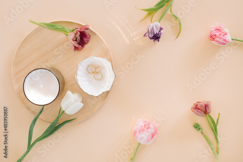 Tulips of different colors  accessories  candle on beige background with copy space. Flat lay  top view minimal trendy fashion collage.