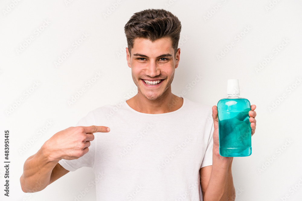 Young caucasian man holding mouthwash isolated on white background person pointing by hand to a shirt copy space, proud and confident Young caucasian man holding mouthwash isolated on white background person pointing by hand to a shirt copy space, proud and confident
