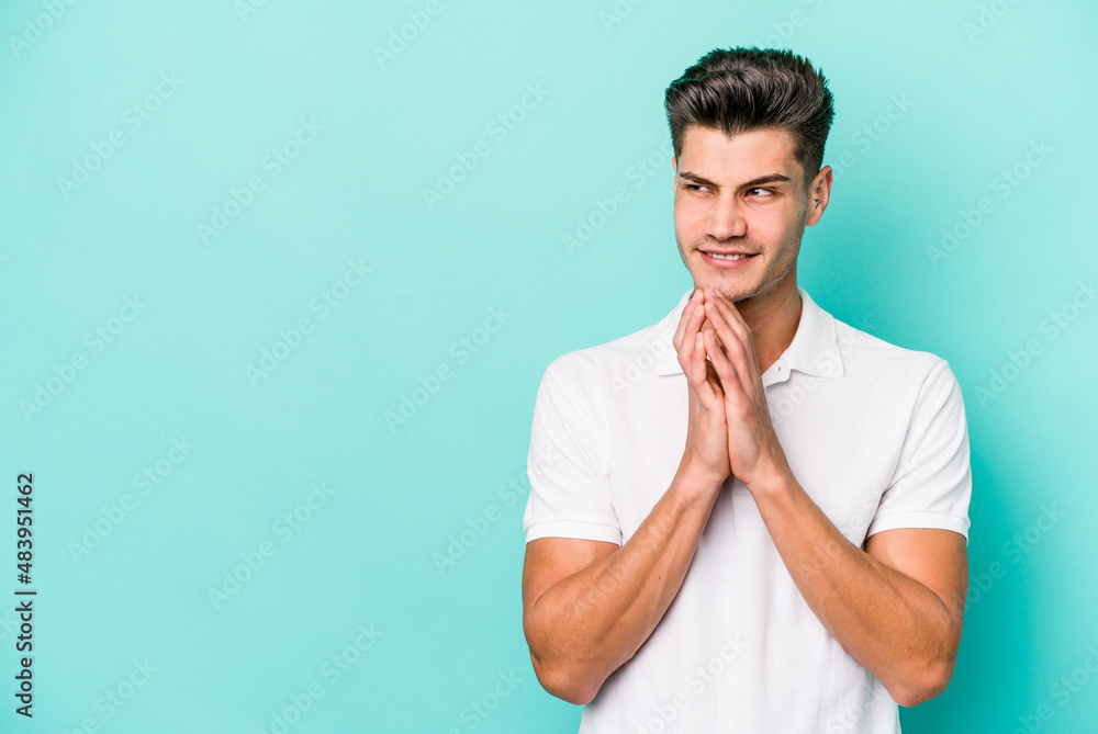 Young caucasian man isolated on blue background making up plan in mind, setting up an idea. Young caucasian man isolated on blue background making up plan in mind, setting up an idea.