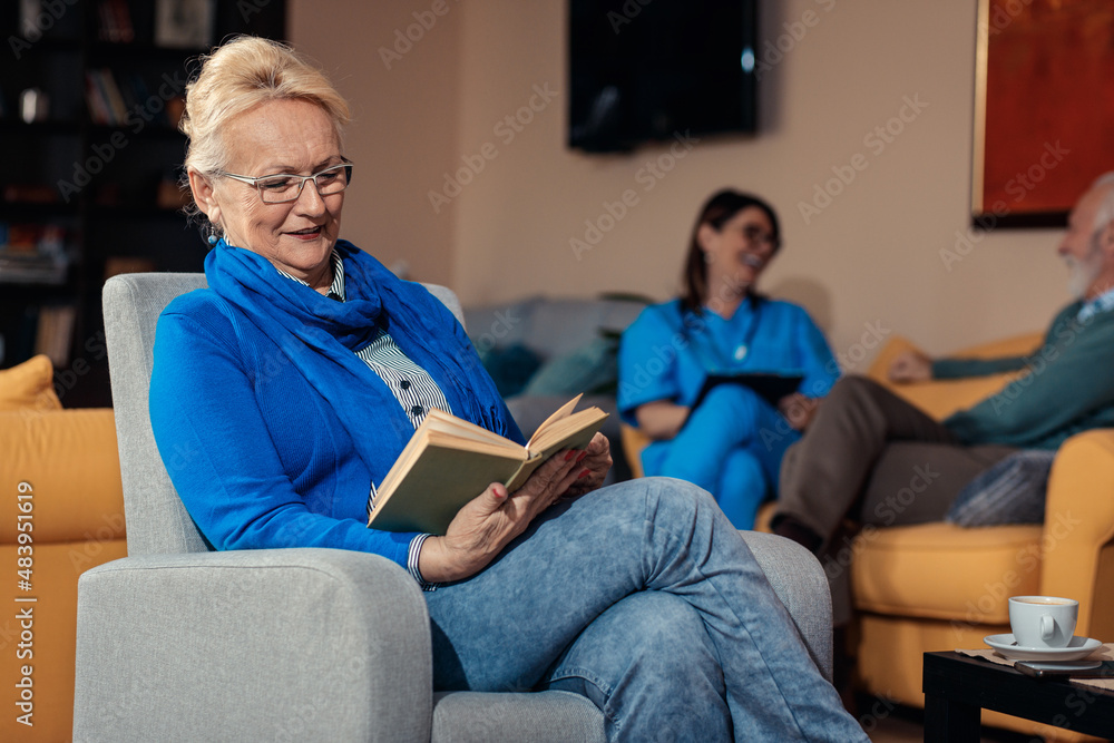 Smiling senior woman siting in nursing home reading a book.