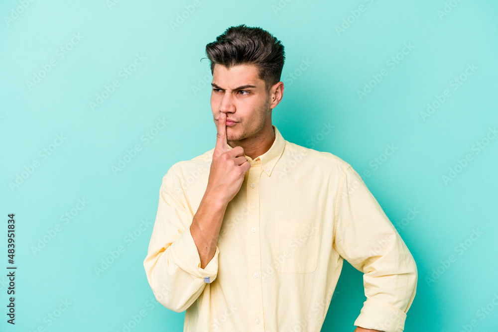Young caucasian man isolated on blue background keeping a secret or asking for silence. Young caucasian man isolated on blue background keeping a secret or asking for silence.