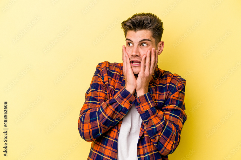 Young caucasian man isolated on yellow background scared and afraid. Young caucasian man isolated on yellow background scared and afraid.