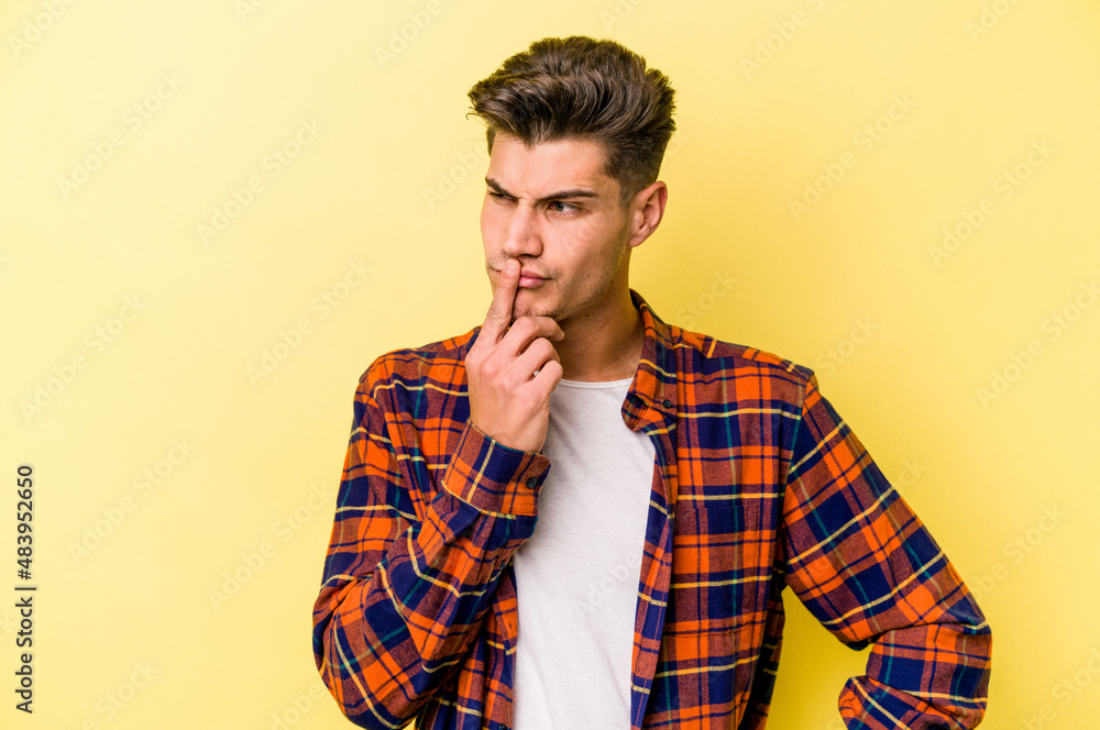 Young caucasian man isolated on yellow background keeping a secret or asking for silence. Young caucasian man isolated on yellow background keeping a secret or asking for silence.