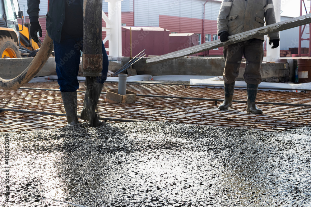 Builders workers pour concrete floor in industrial Legs in