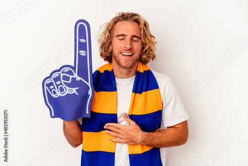 Young sports caucasian fan man isolated on white background laughs out loudly keeping hand on chest.