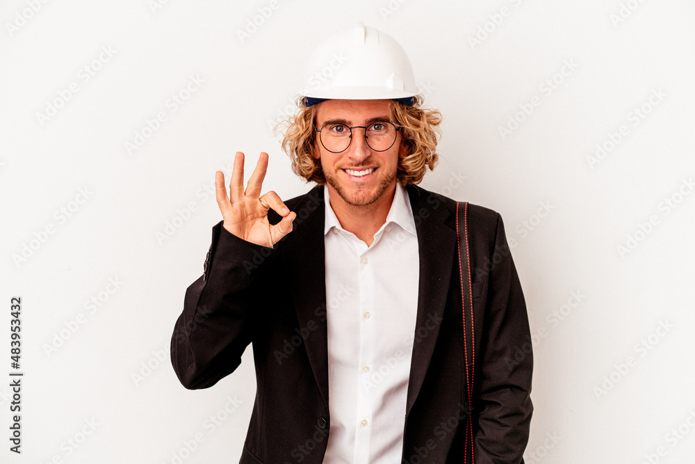 Young architect caucasian man with helmet isolated on white background cheerful and confident showing ok gesture.