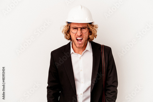 Young architect caucasian man with helmet isolated on white background screaming very angry and aggressive. © Asier