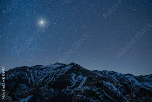 Fototapeta night sky full of stars over snow mountains in winter