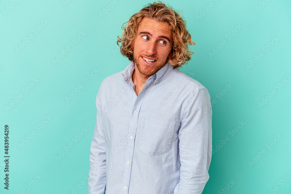 Young caucasian man isolated on blue background laughs and closes eyes, feels relaxed and happy. Young caucasian man isolated on blue background laughs and closes eyes, feels relaxed and happy.