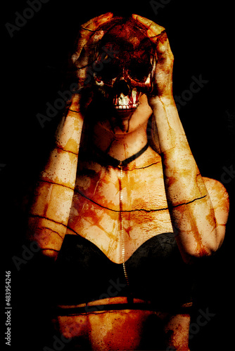 Woman holding bloody skull against dark background photo