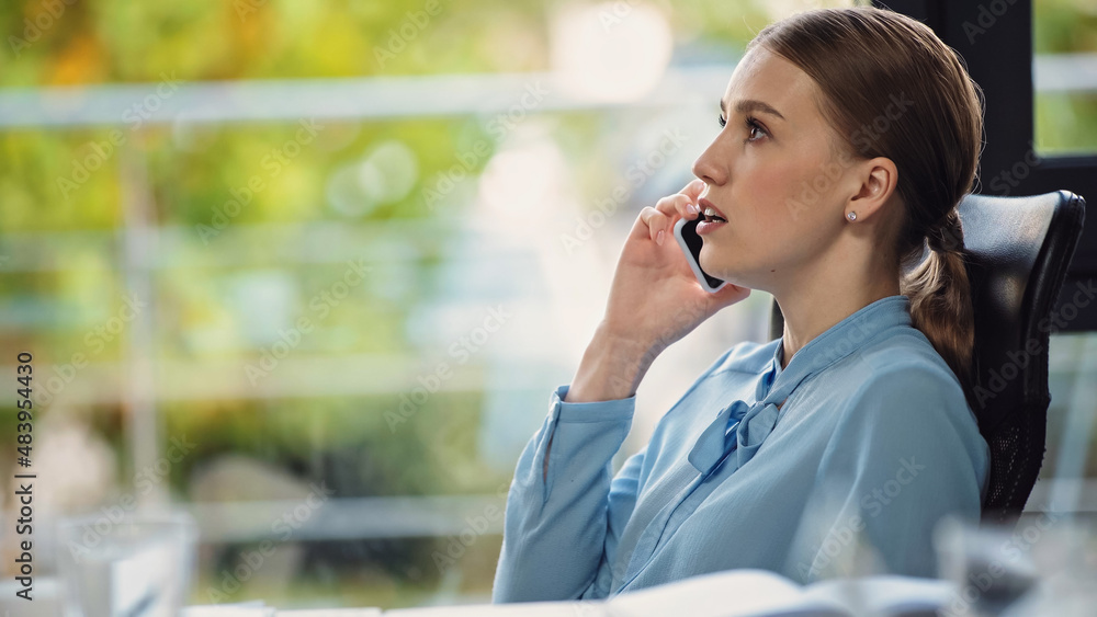 side view of young businesswoman talking on smartphone in office side view of young businesswoman talking on smartphone in office
