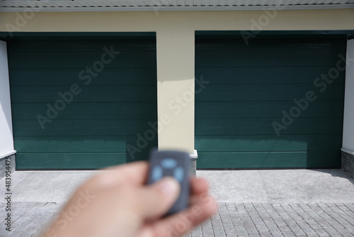 The hand tries to open the garage door with the remote control. Garage with two gates, double. photo