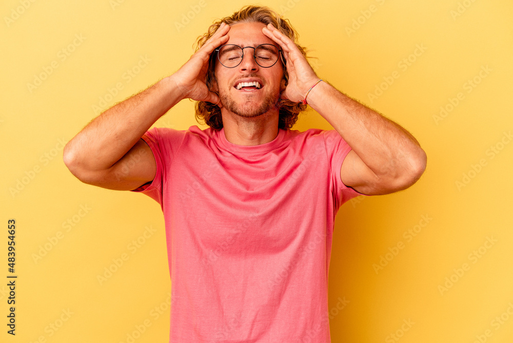 Young caucasian man isolated on yellow background laughs joyfully keeping hands on head. Happiness concept. Young caucasian man isolated on yellow background laughs joyfully keeping hands on head. Happiness concept.