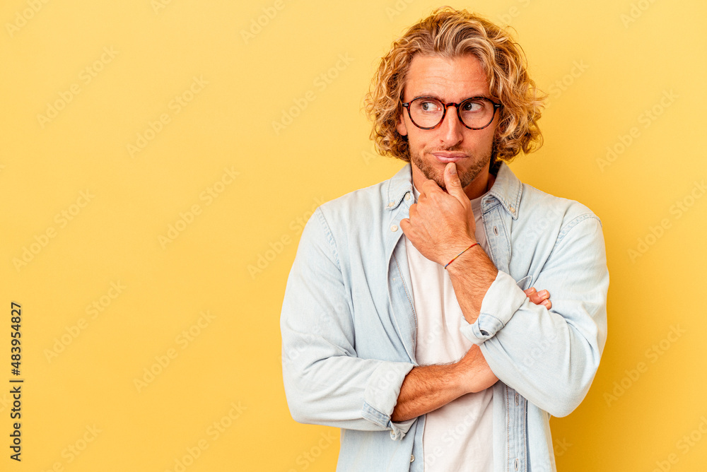 Young caucasian man isolated on yellow background looking sideways with doubtful and skeptical expression. Young caucasian man isolated on yellow background looking sideways with doubtful and skeptical expression.