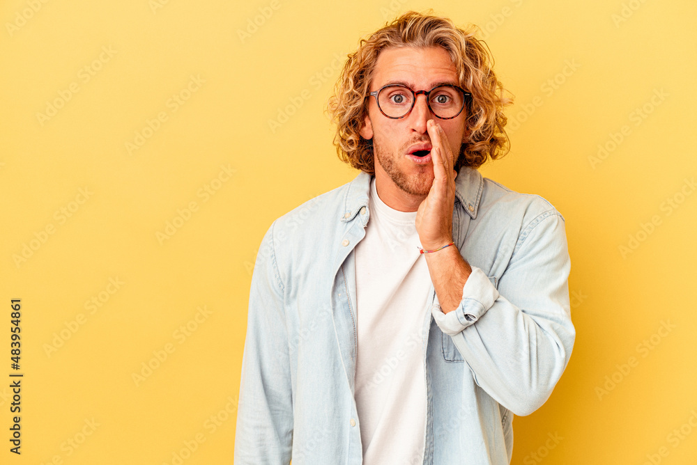Young caucasian man isolated on yellow background is saying a secret hot braking news and looking aside Young caucasian man isolated on yellow background is saying a secret hot braking news and looking aside