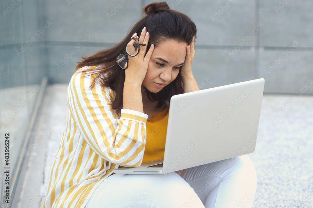 Upset with negative emotions fat woman have a problem, working remotely on a laptop. Closeup tired millennial overweight girl holding in eyeglasses, wears striped shirt, yellow top and white pants Upset with negative emotions fat woman have a problem, working remotely on a laptop. Closeup tired millennial overweight girl holding in eyeglasses, wears striped shirt, yellow top and white pants