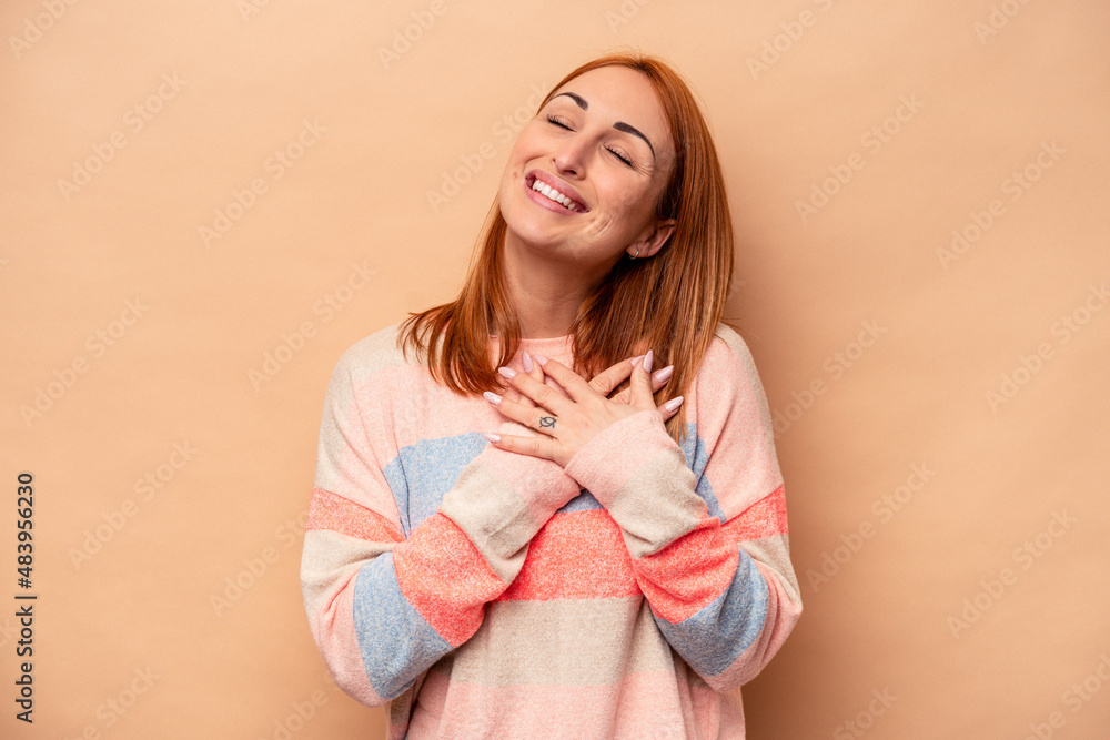 Young caucasian woman isolated on beige background has friendly expression, pressing palm to chest. Love concept. Young caucasian woman isolated on beige background has friendly expression, pressing palm to chest. Love concept.