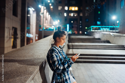 Woman with a smartphone in the night city