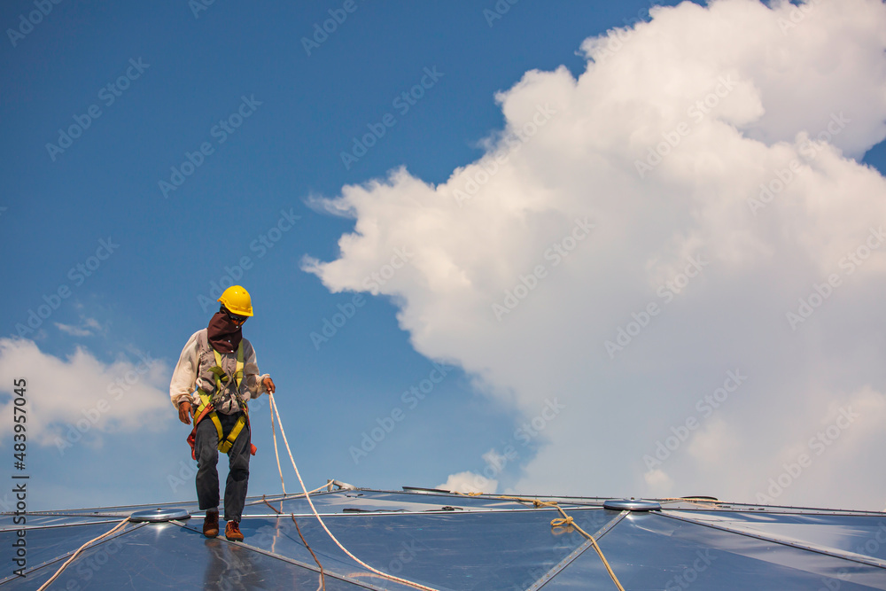 Male workers rope access height safety connecting with a knot safety harness, to ascending, construction site oil tank dome. Male workers rope access height safety connecting with a knot safety harness, to ascending, construction site oil tank dome.