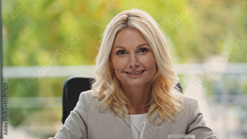 blonde middle aged businesswoman smiling at camera in office